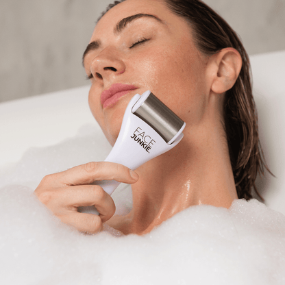 Close-up of a woman relaxing in a bubble bath while using the Face Junkie ice roller on her face. The stainless steel facial roller helps reduce puffiness, soothe the skin, and promote circulation for a refreshed and radiant complexion. Face Junkie promotes self-care and holistic skincare rituals, integrating cooling therapy for a rejuvenating beauty routine.